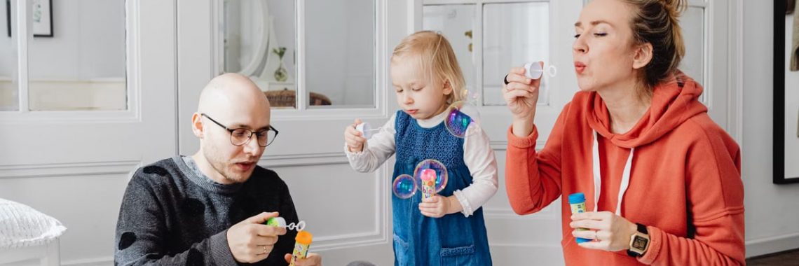 Family enjoying quality time blowing bubbles indoors, capturing joyful moments.